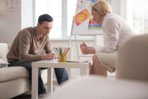 a woman and man draw sketches at a table