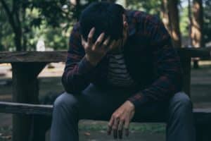 a person holds their head on a bench struggling with gateway drugs