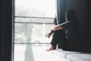 a person looks out of a window while sitting in bed possibly pondering the history of heroin