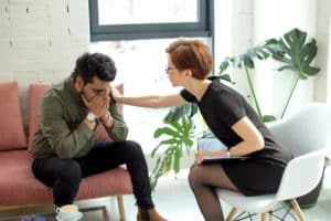 a woman consoles a man holding his head