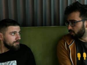 a couple of men sitting on a green couch hosting drug intervention for loved one