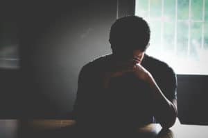 a person holds their head on a table needing things to know about addiction