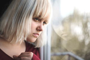 Person looking out window and thinking about the link between addiction and genetics