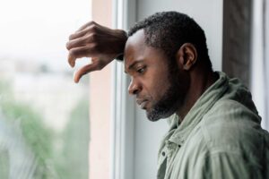 Man leaning against window, thinking about the signs to get sober he's been experiencing