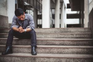 a person sits on steps looking down dealing with scopolamine side effects