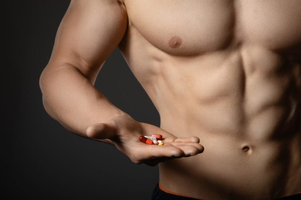 a muscular person holds a handful of pills which begs the question are steroids addictive