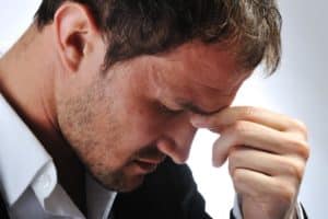 a person holds their head in anguish potentially suffering from symptoms of alcoholic hepatitis