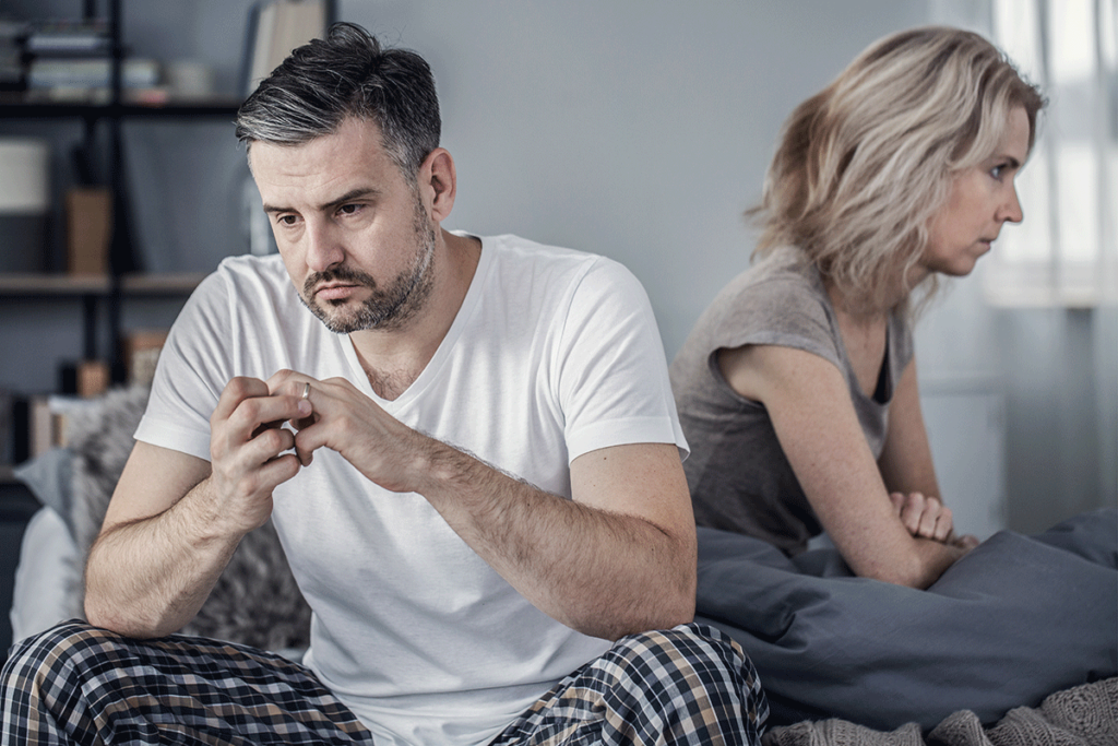 a couple looks away from each other on a couch possibly struggling with marriage and sobriety