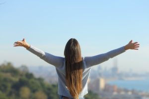 a person stretches their arms at a scenic view after reading about how to forgive yourself in addiction recovery
