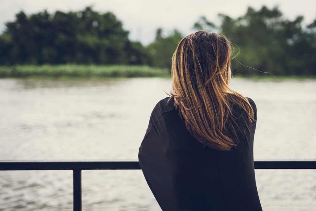 a person leans on a fence overlooking the water possibly after learning about the risks of dissociative drugs