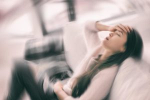a person holds their head as they deal with the 9 signs of alcohol poisoning