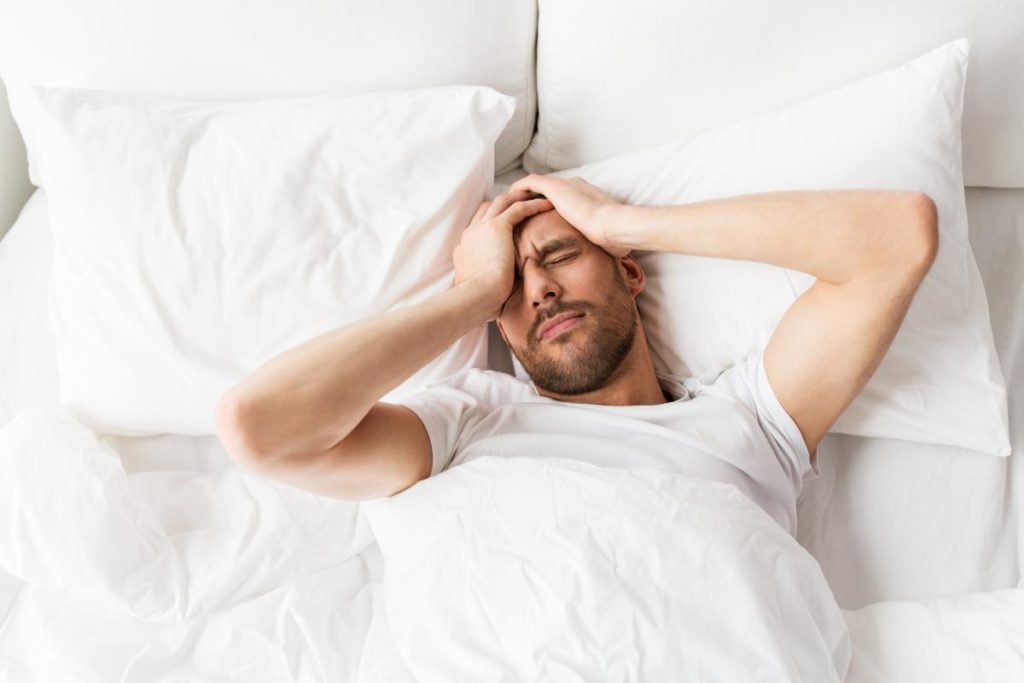 a person lies in bed holding their head potentially wondering what is blackout drinking