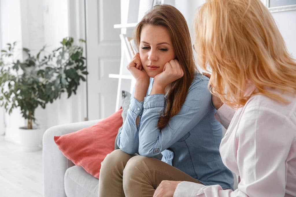 two people sit on a couch possibly during clonidine addiction treatment