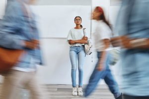 a person stands still pondering the link between college students and addiction while others move quickly past