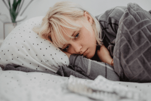 a person lays in bed looking tired possibly struggling with health problems caused by alcohol abuse