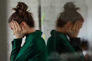 Person with face in hands, experiencing signs of co-occurring disorders