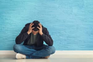 Person sitting on floor and observing the signs of cocaine withdrawal in themselves