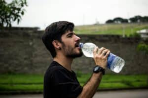 A young man detoxing from alcohol by drinking water to repair his liver