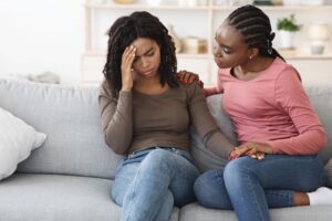 signs of alcoholism in a friend - two friends sit on a couch acting concerned
