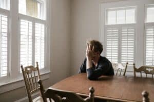 A young man experiencing anxiety in addiction recovery in his parents' dining room