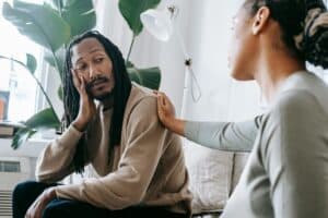 A woman reaching out to a frustrated man as she tries to help an alcoholic get sober