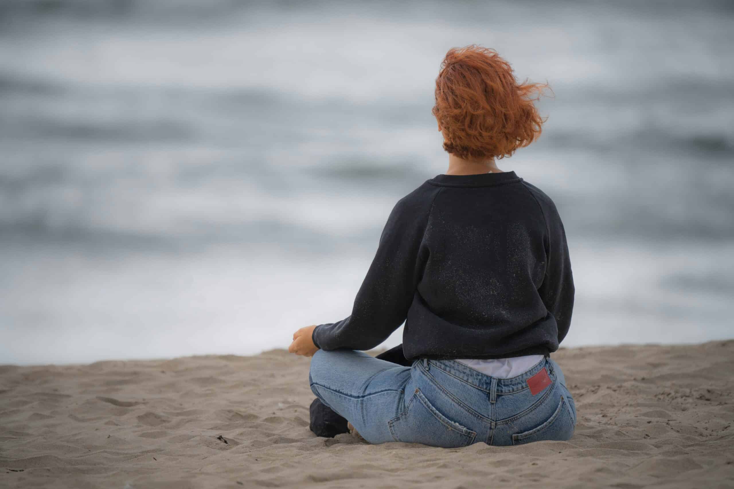 woman sitting cross-legged on the beach
