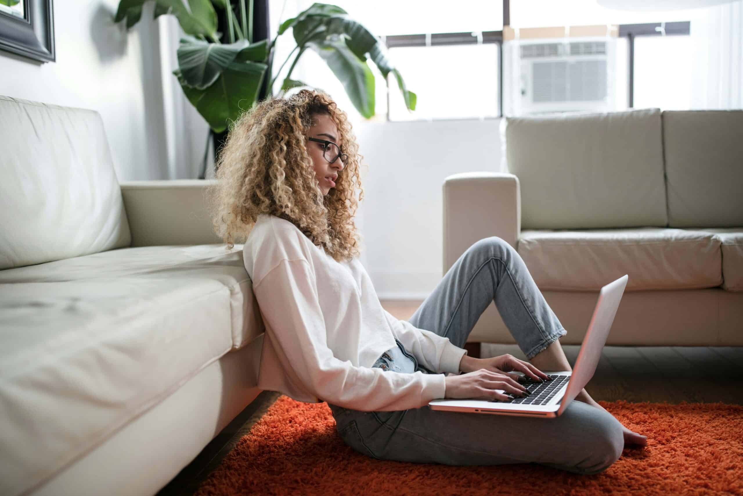 A woman sitting on the floor of her living room using her laptop to access virtual IOP